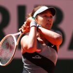 A young woman swings a tennis racket.